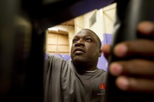 Dionysus Sisson, 40, repairs a basketball goal in the gym at Olivet Fellowship Baptist Church, one of more than a dozen gyms where he works with Memphis Athletic Ministries. Photo by Brandon Dill